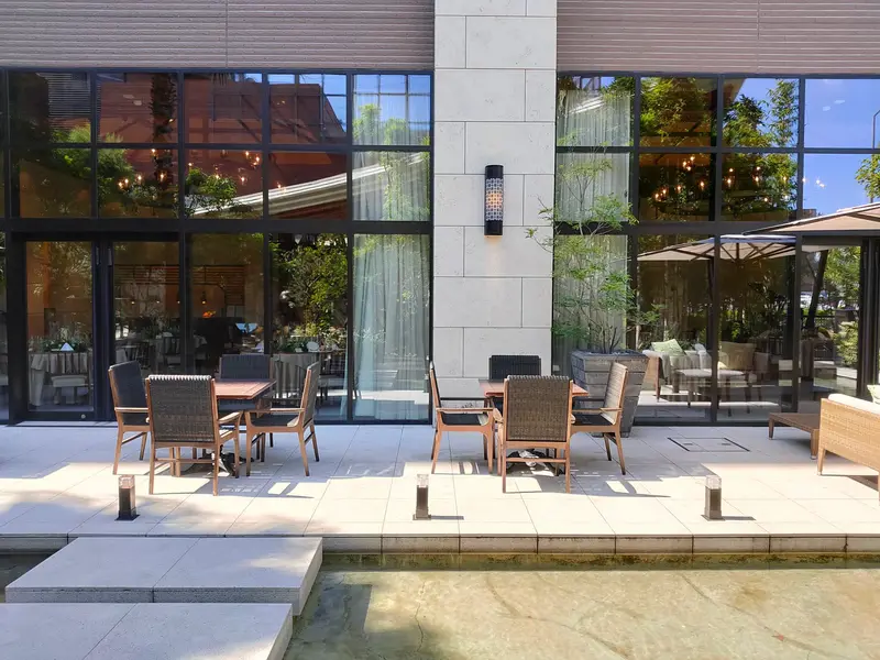 Bašta restorana uz staklenu fasadu, sa stolovima i stolicama