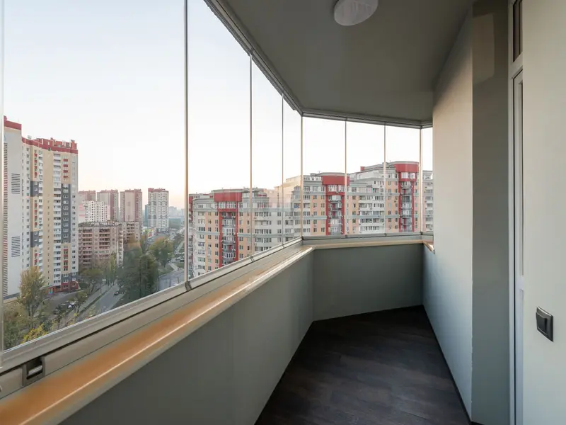 Ostakljen balkon u stanu, staklena krila bez okvira i pogled na zgrade